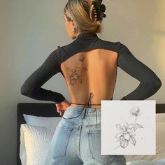 a woman standing in front of a bed with her back turned to the camera and tattoos on her body