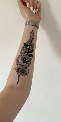 a woman's arm with a snake and roses tattoo on the left side of her arm