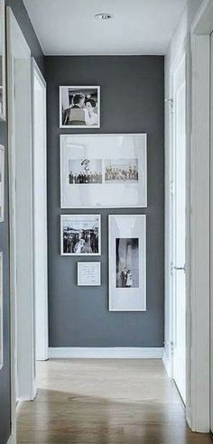 an empty hallway with pictures on the wall and wood flooring in front of it