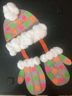 a pair of mittens made out of cotton balls and felt with pom poms on them