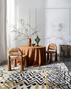 a table with two chairs and a vase on it in front of a white wall