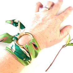 a woman's hand with green and white bracelets wrapped around her wrist on top of a table