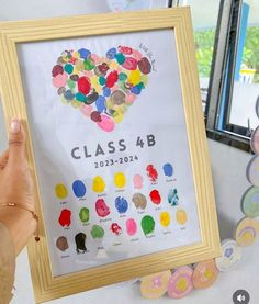 a person holding up a framed art piece with the words class 4b in it