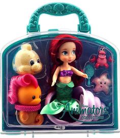 the little mermaid doll is in its plastic case with other toys around it, including an animal