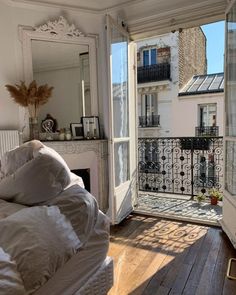 an open door leading to a balcony with white furniture and pillows on top of it