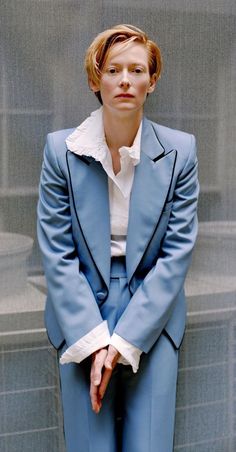 a woman in a blue suit and white shirt is posing for a photo with her hands on her hips