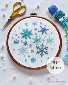 a cross stitch pattern with snowflakes on it and some scissors next to it