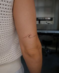 a woman with a small wave tattoo on her arm