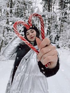 a woman holding two candy canes in the snow