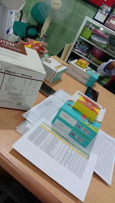 a person sitting at a table with several boxes and papers on top of the desk