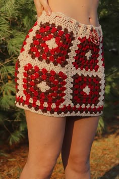 a woman is standing in front of a tree wearing a crocheted skirt with hearts on it