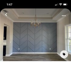 an empty room with wood flooring and blue wall art on the walls, along with a chandelier