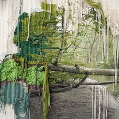 an art work with green and white yarns hanging from the side of a tree