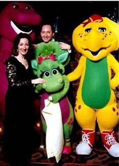 three people standing next to each other in front of two large stuffed animals and one woman