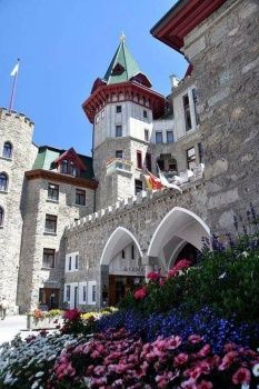 a castle like building with lots of flowers in the foreground