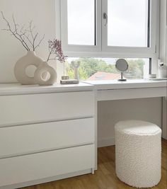 a white desk with a vase and mirror on it next to a window sill