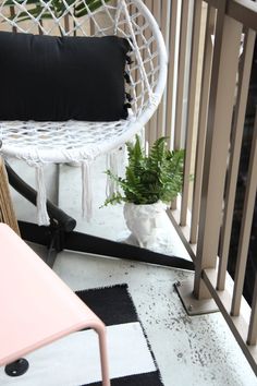 a white chair sitting on top of a balcony next to a potted plant