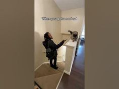 a woman standing in front of a cat on top of a stair case next to a doorway