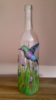 a glass bottle with a painting of a hummingbird on it