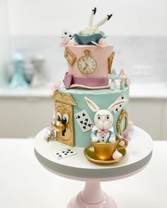 a three tiered cake decorated with an animal and clock on it's side