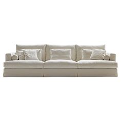 a white couch with several pillows on it's back and arms, in front of a