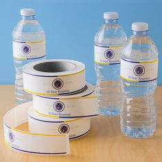 three bottled water bottles sitting on top of a table next to two rolls of paper