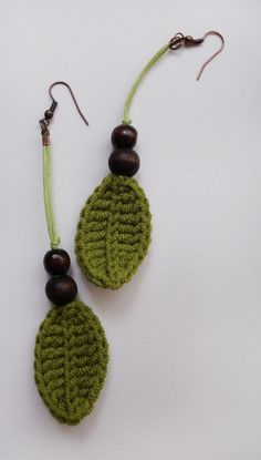 two green earrings with wooden beads hanging from the earwires on a white background