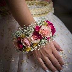 a bride's bouquet with pink roses and baby's breath in her hand