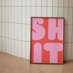 a pink and red poster sitting on top of a tiled floor next to a white wall