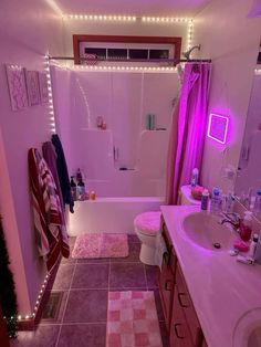 a bathroom with pink lights on the ceiling and rugs in front of the bathtub