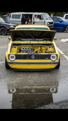 a yellow car with its hood open in a parking lot