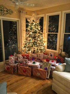 a living room filled with lots of presents under a christmas tree in front of a window