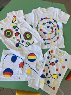 three children's t - shirts with different designs on them sitting on a table