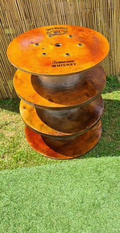 three metal discs stacked on top of each other in front of a wooden fence and grass