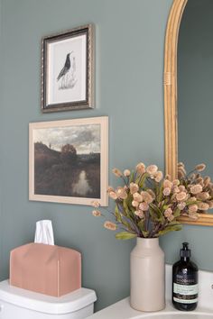 there is a vase with flowers in it on the bathroom counter next to the sink