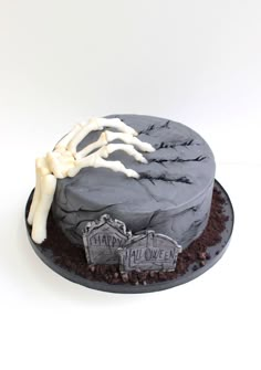 a halloween cake decorated with skeleton hands and tombstones on it's side, in front of a white background