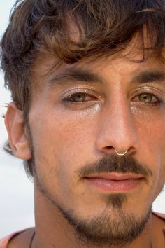 a close up of a man with a nose ring on his nose and piercing in the middle