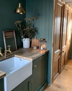 a kitchen with green painted walls and wooden counter tops, gold faucets and brass fixtures