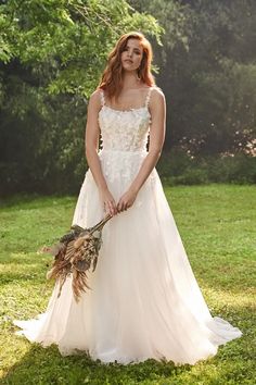 a woman in a wedding dress is holding a bouquet and posing for the camera with her hands on her hips