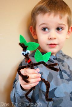 a young boy is holding up some felt animals that are made to look like leaves