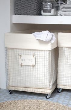 two white baskets sitting on top of each other in front of a shelf filled with towels