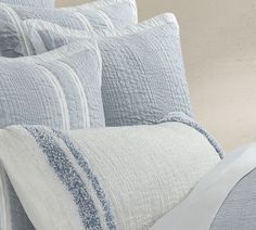 a close up of a bed with blue and white pillows