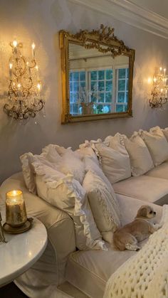 a white couch with pillows and a dog laying on it's side in front of a mirror