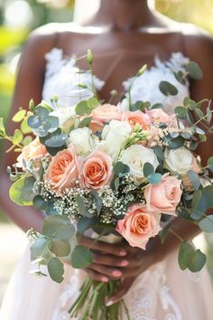 a woman holding a bouquet of flowers in her hands with greenery on the side