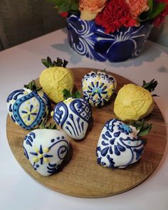 some strawberries are sitting on a wooden plate next to a blue and white vase