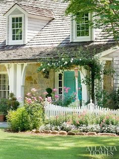 a white house with green shutters and flowers