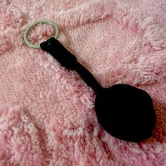 a keychain shaped like a spoon laying on top of a pink fuzzy blanket