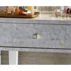 a white marble dresser with gold handles and knobs on the top, in front of a mirror