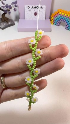 a hand holding a beaded necklace with flowers on it