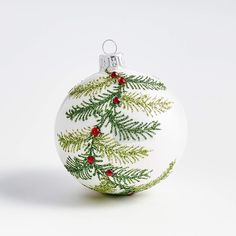 a white ornament with green leaves and red berries